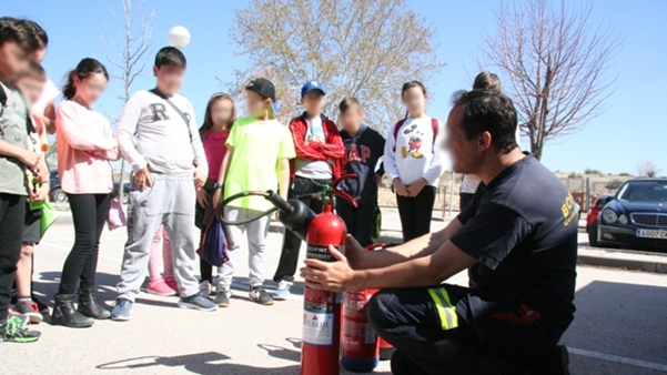 Bombero enseñando el manejo de un extintor a escolares